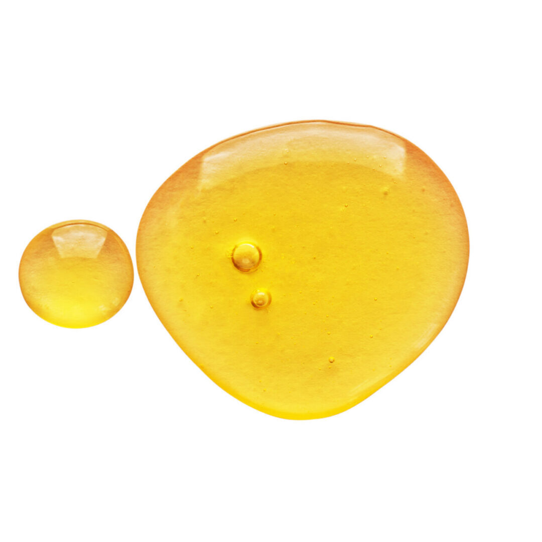 Golden baobab oil droplets on a white background